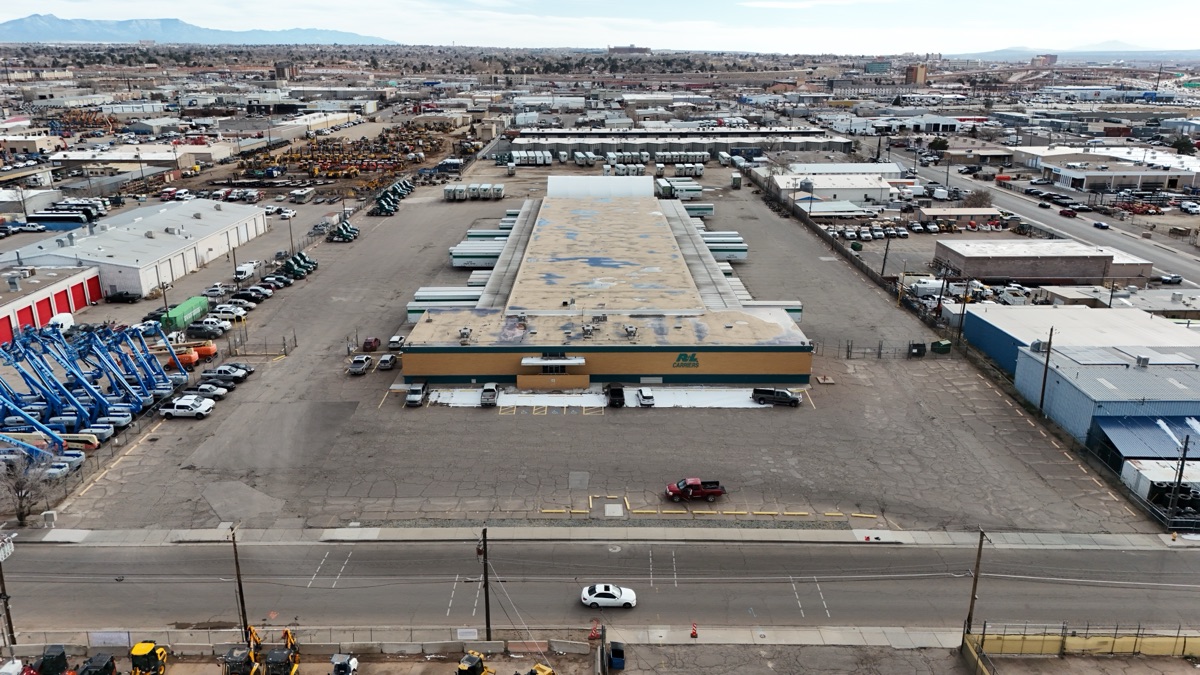 Wide aerial of an Albuquerque logistics facility with the industrial district and mountains behind