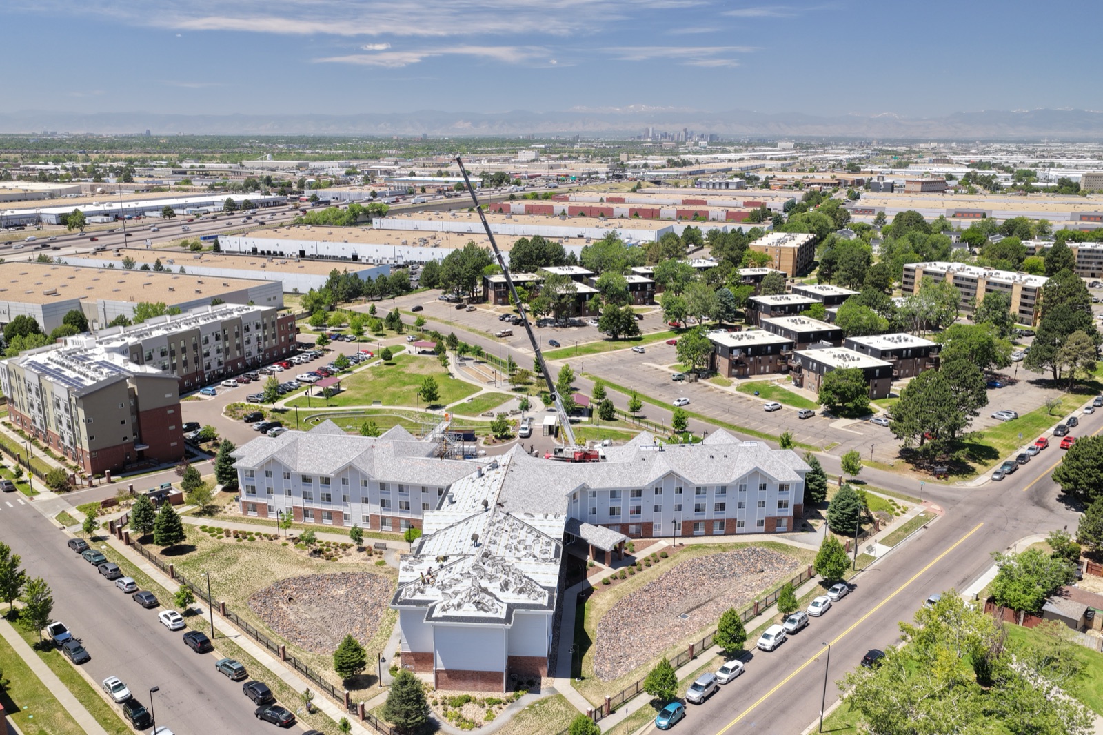 Aerial drone view of a multifamily commercial re-roof in northeast Denver with the Denver skyline and Front Range on the horizon