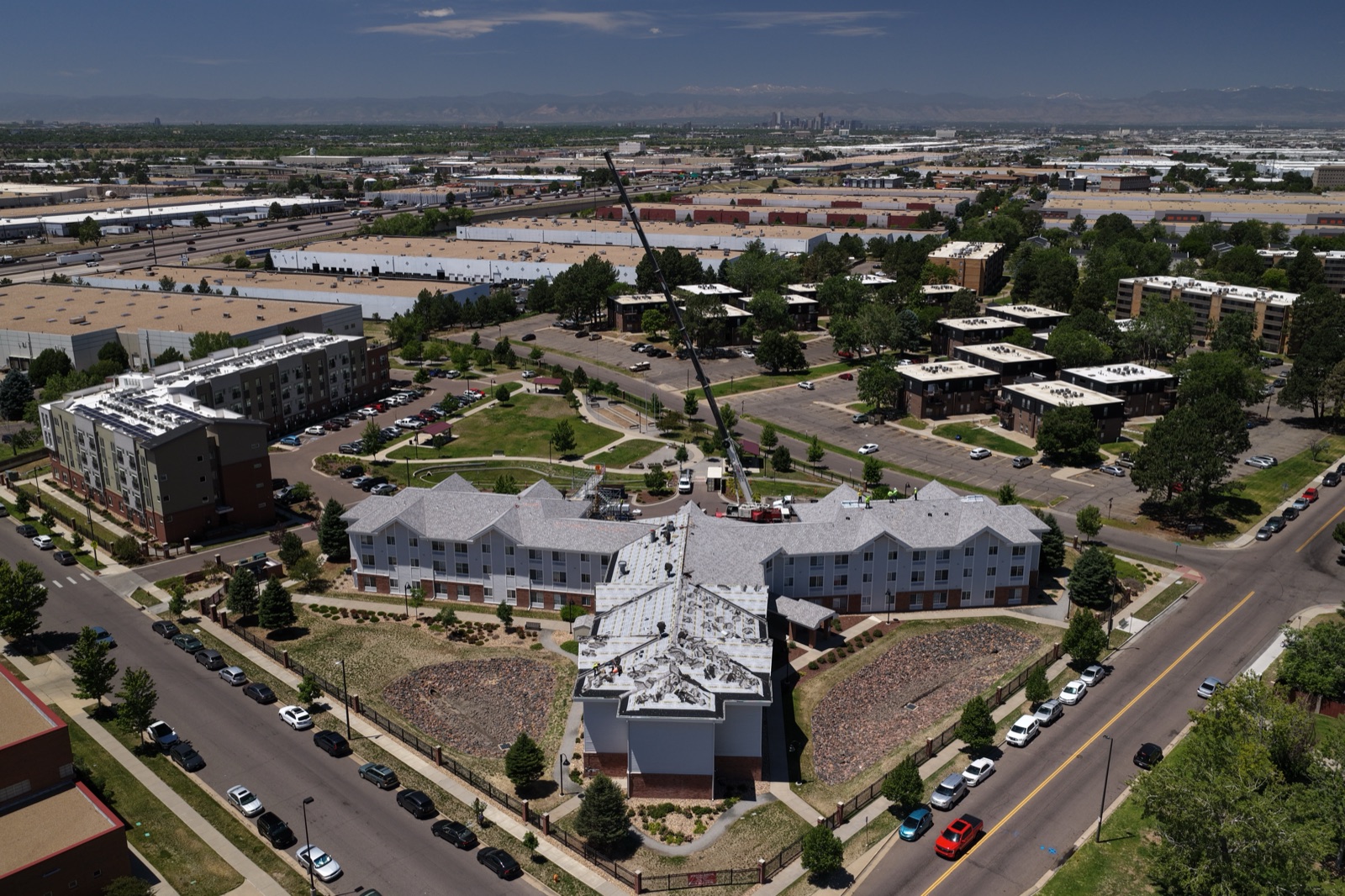 Wide aerial over the Denver metro with a crane and the Front Range on the horizon