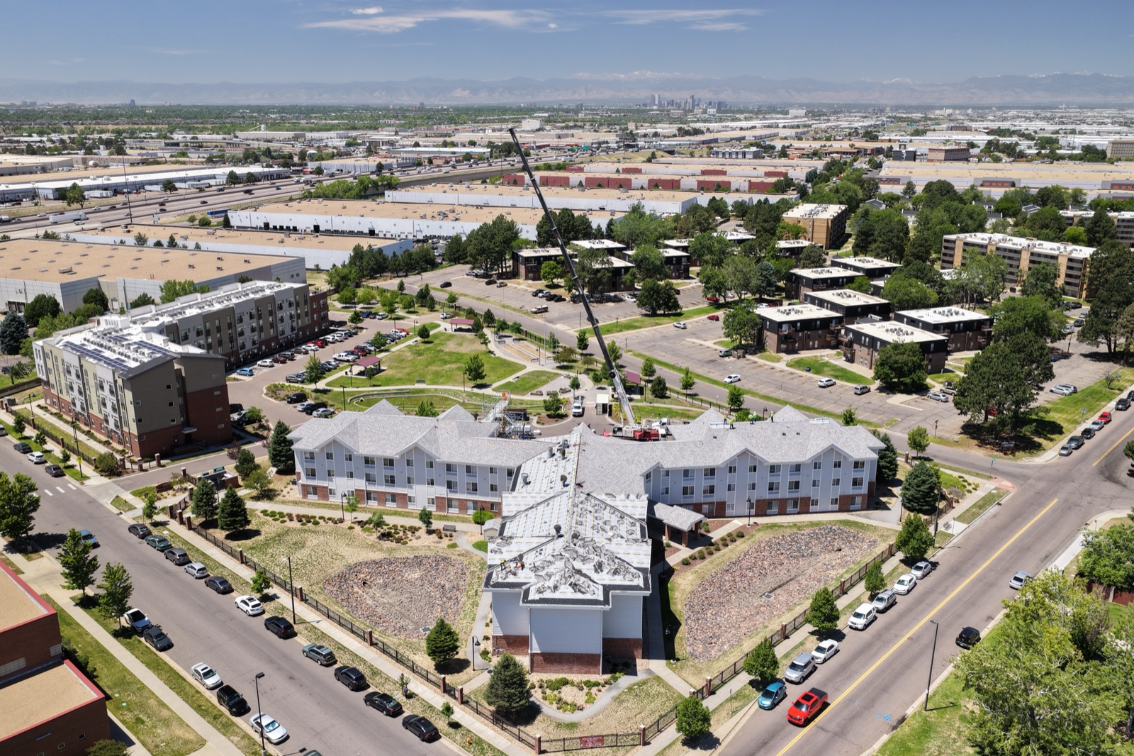 Aerial view over a green Denver metro neighborhood with the Rocky Mountains in the background