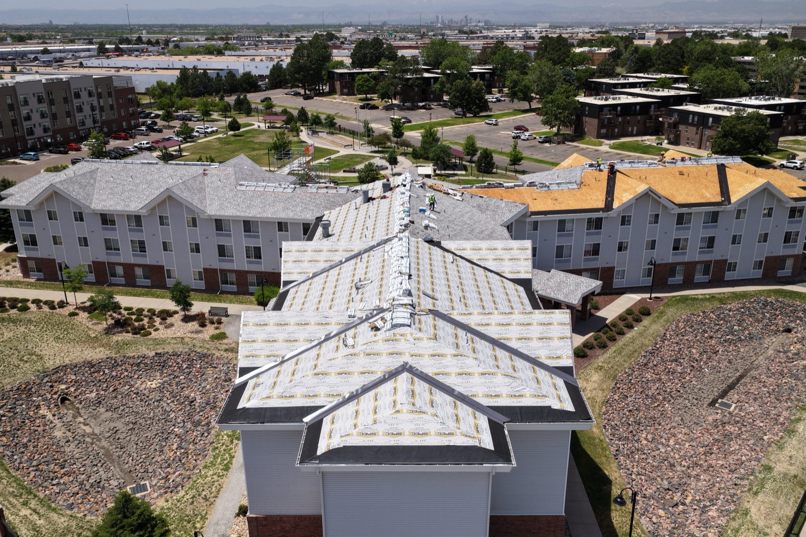 Drone photo of roofing crews installing underlayment on a large multifamily building in the Denver metro