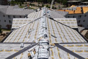 Low-altitude drone detail of roof deck and synthetic underlayment with material staging during a Denver re-roof