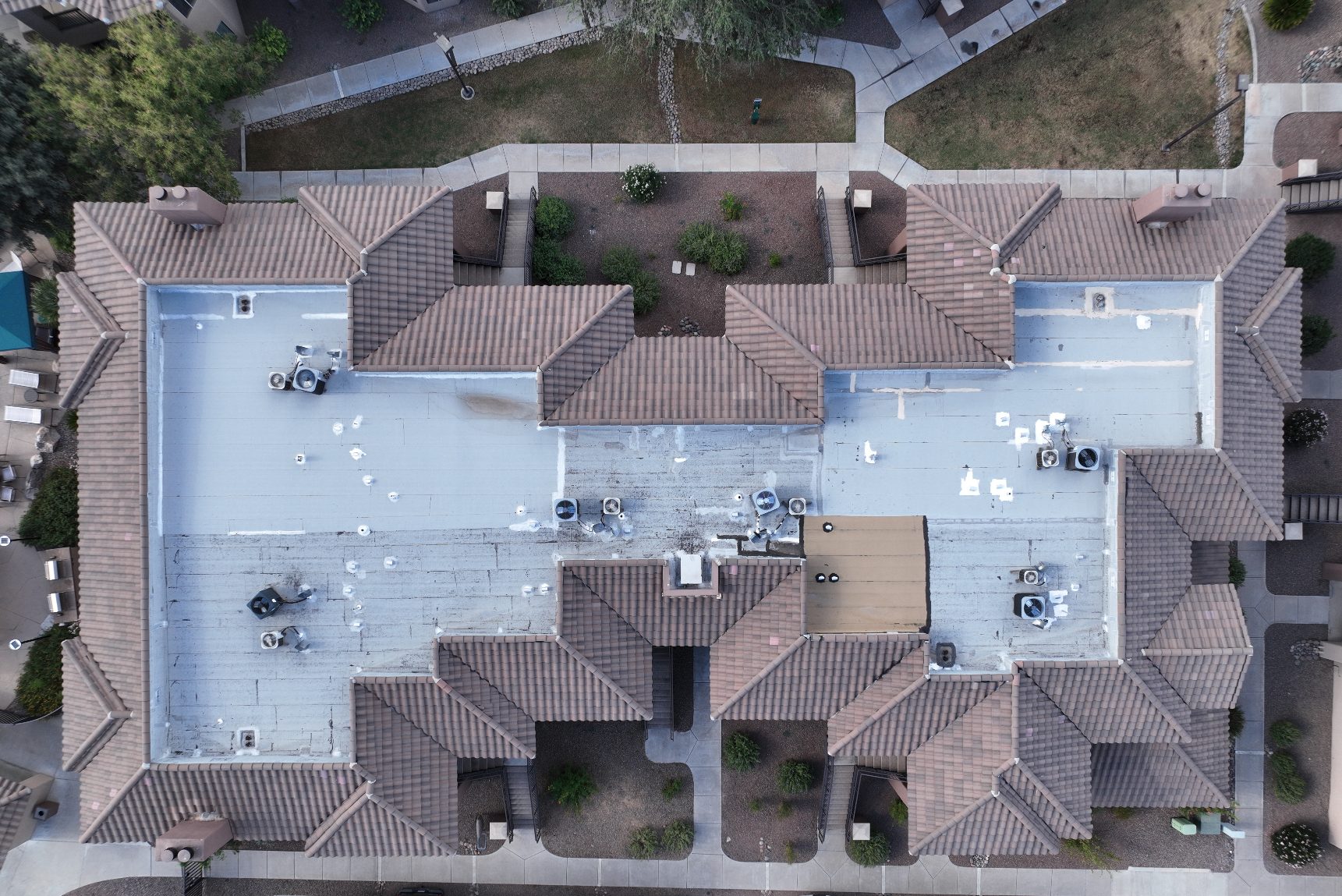 Top-down aerial of a white flat roof residential complex with parapet walls