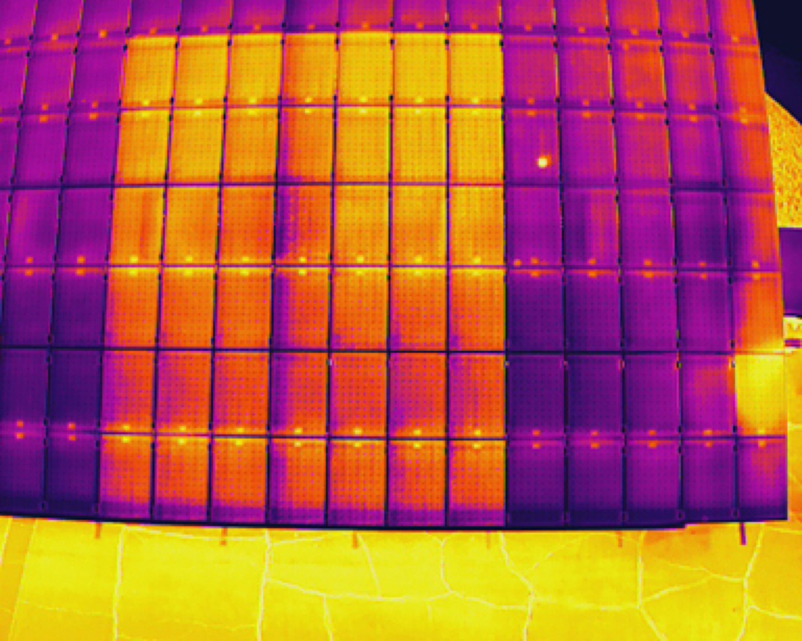 Thermal drone image of a flat commercial roof with solar array and equipment heat signatures