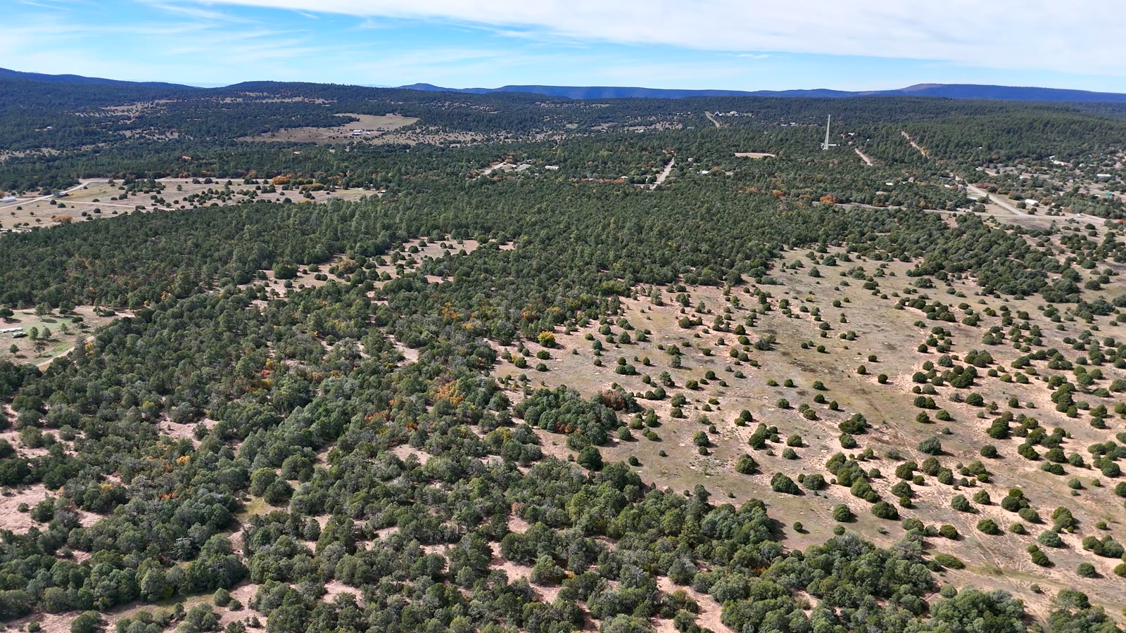 Low-level drone sweep over piñon-covered East Mountains terrain
