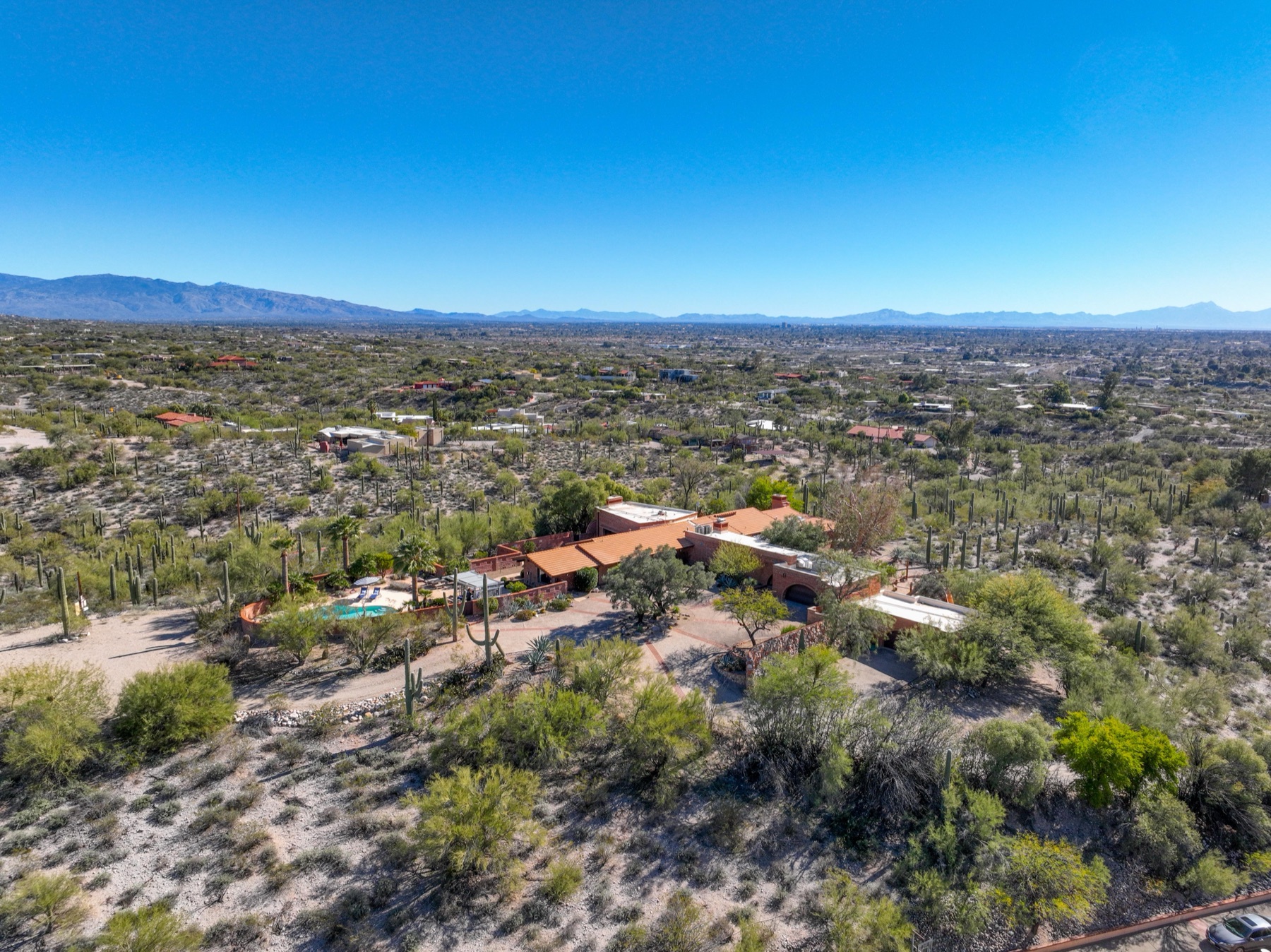Aerial over a Catalina Foothills estate with pool amid saguaros and mountain views